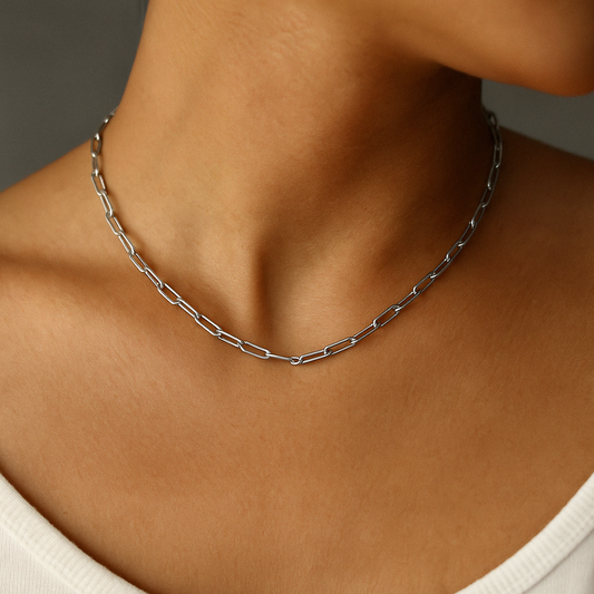 Silver chain necklace on a person's neck against a neutral background