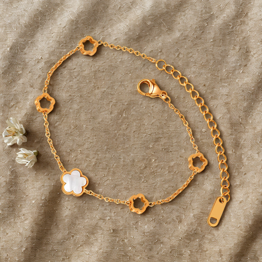 Gold bracelet with floral designs on a textured beige background