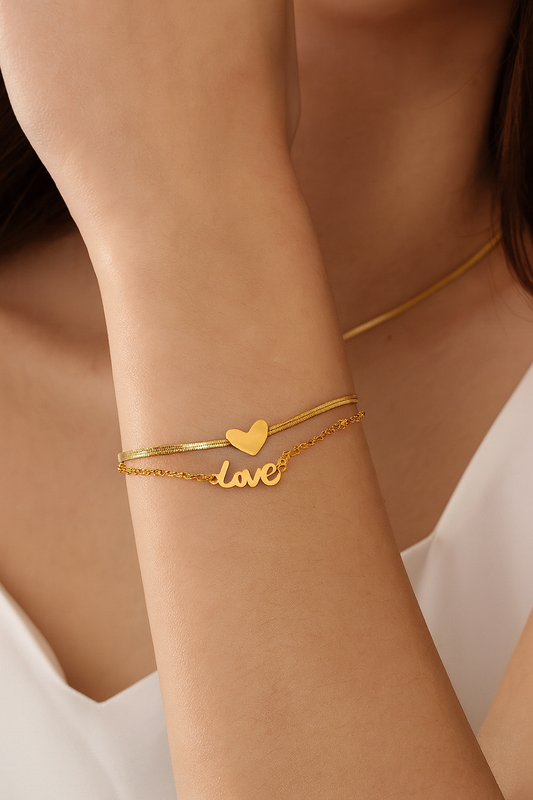 Gold bracelet with heart and 'love' charm on a wrist