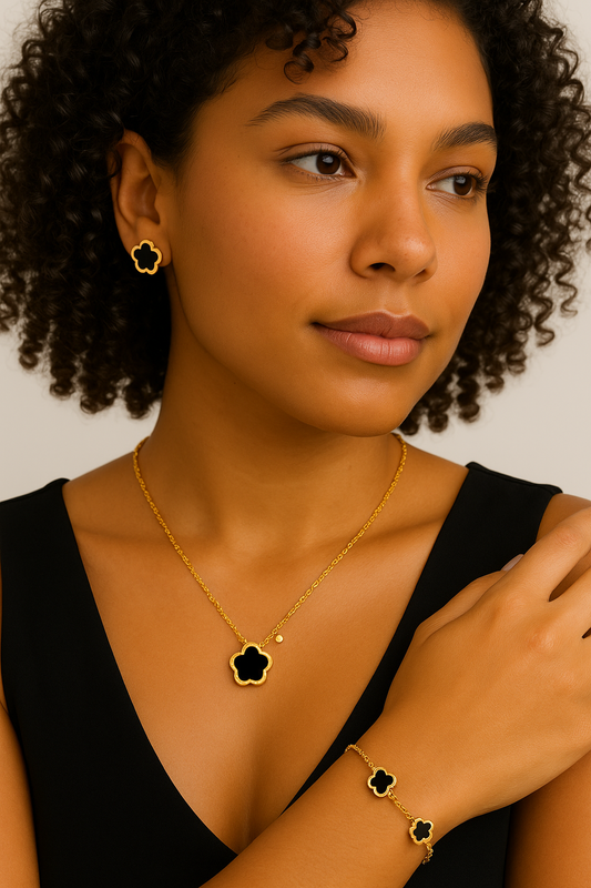 Woman wearing gold jewelry with black clover-shaped pendants on a neutral background