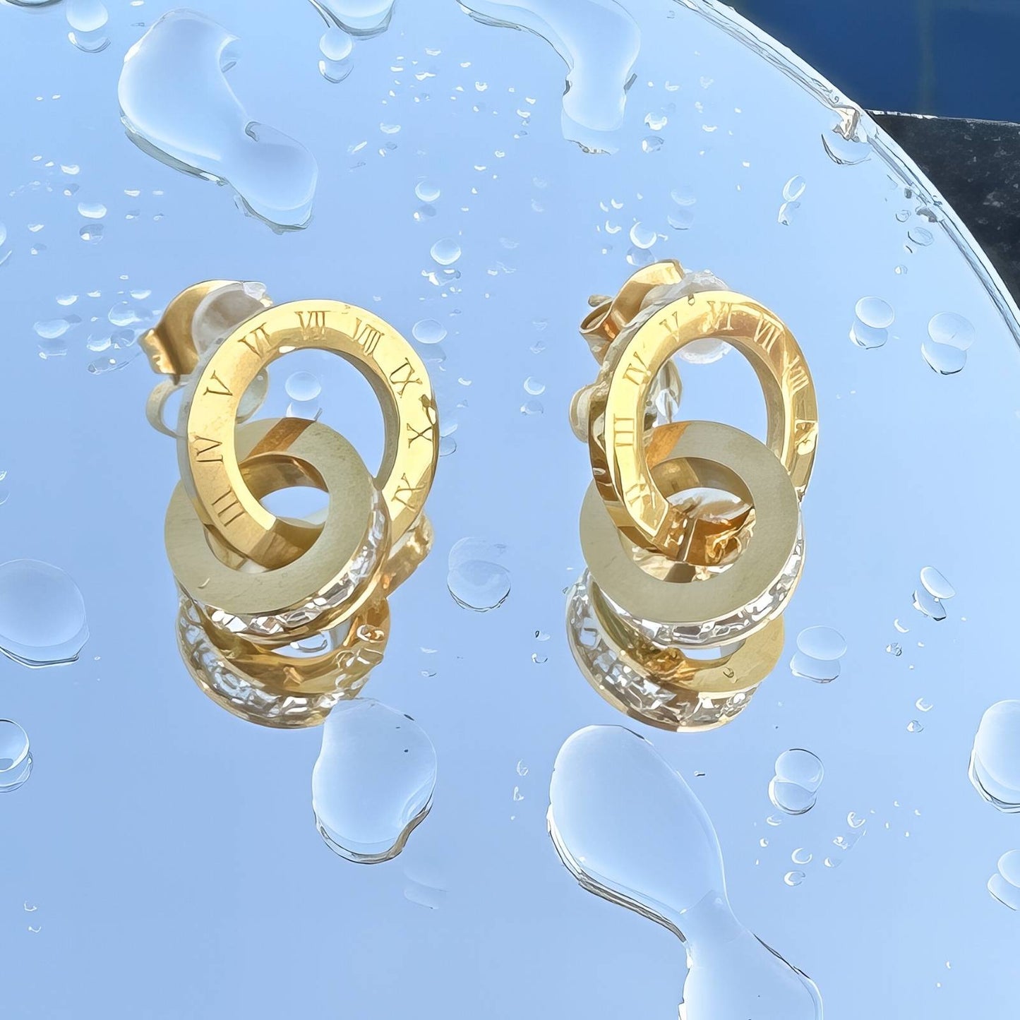 Dual hoop earrings with roman numerals displayed on glass
