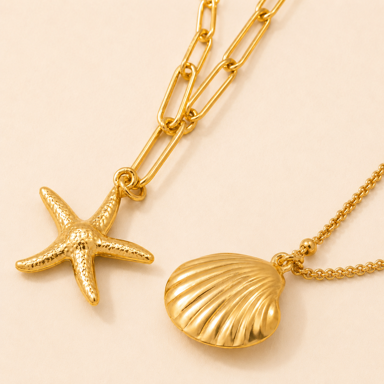 Gold necklace with starfish and shell pendants on a beige background
