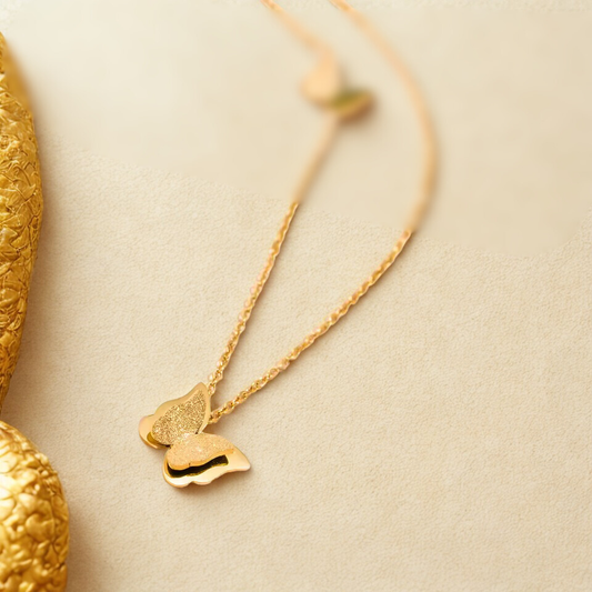 Gold necklace with butterfly-shaped pendant on a beige background