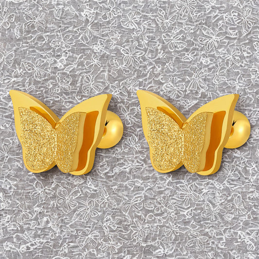Gold butterfly-shaped earrings on a gray floral patterned background