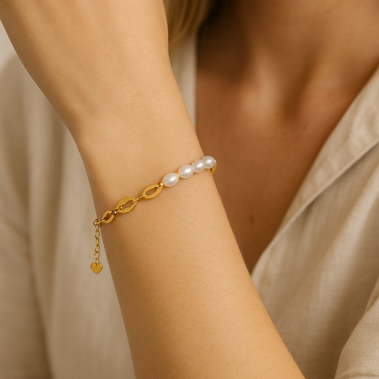 Delicate gold and pearl bracelet styled on wrist with soft lighting