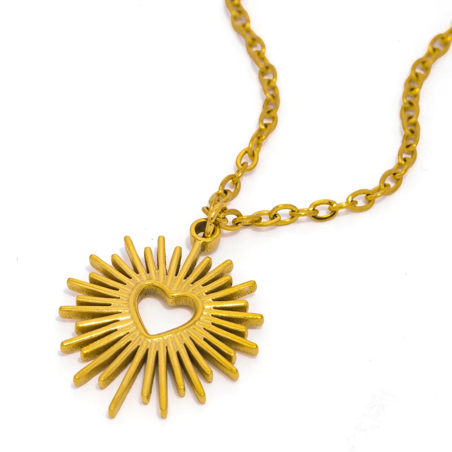 Gold necklace with a sunburst heart pendant on a white background