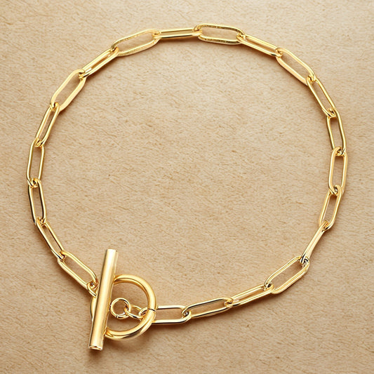 Gold chain bracelet on a beige background