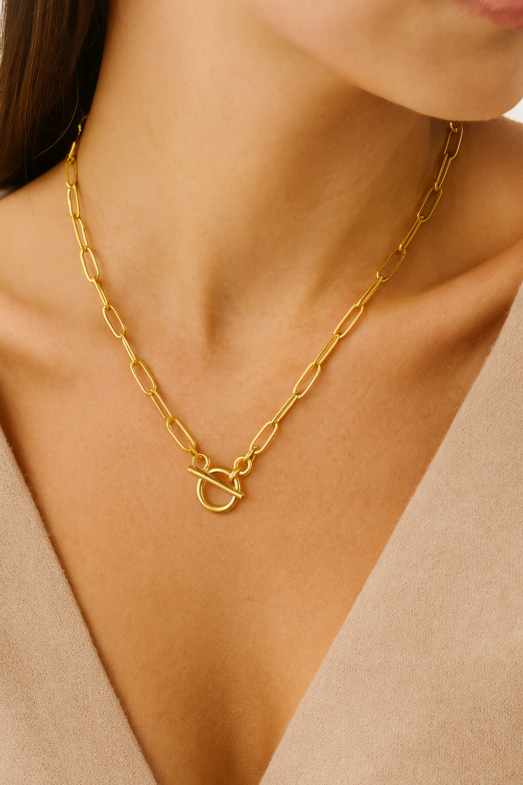 Gold chain necklace worn by a person against a neutral background