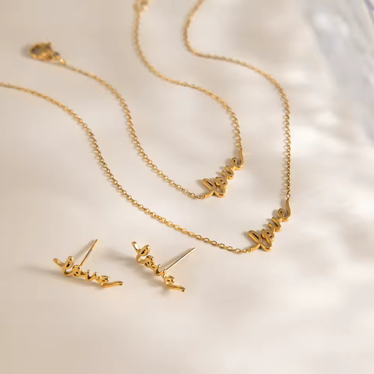 Gold 'love' necklace and earrings on a light background