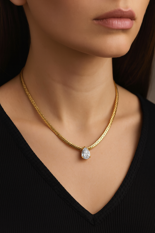 Gold necklace with a diamond pendant worn by a model against a black background