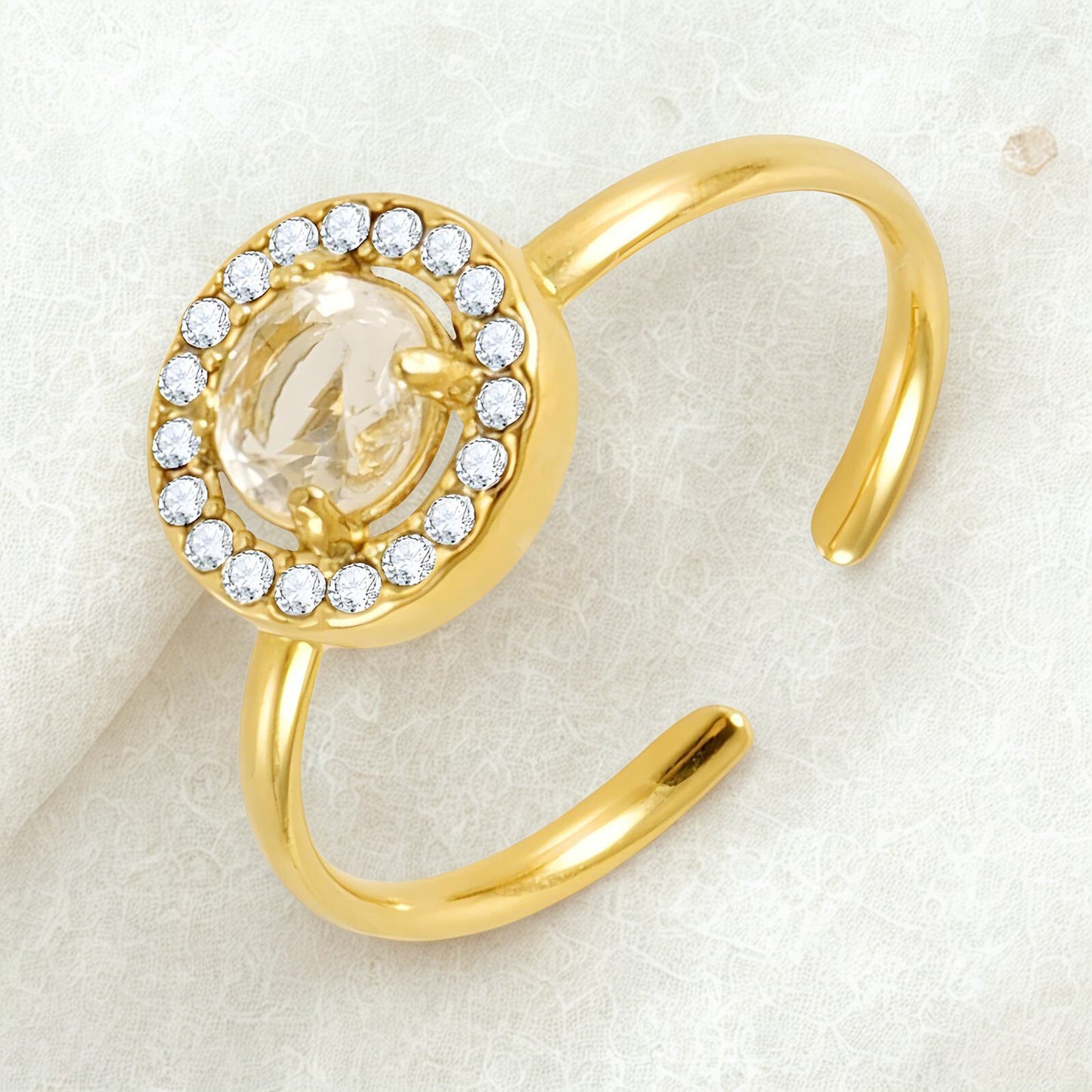 Gold ring with a central gemstone and diamond accents on a light background