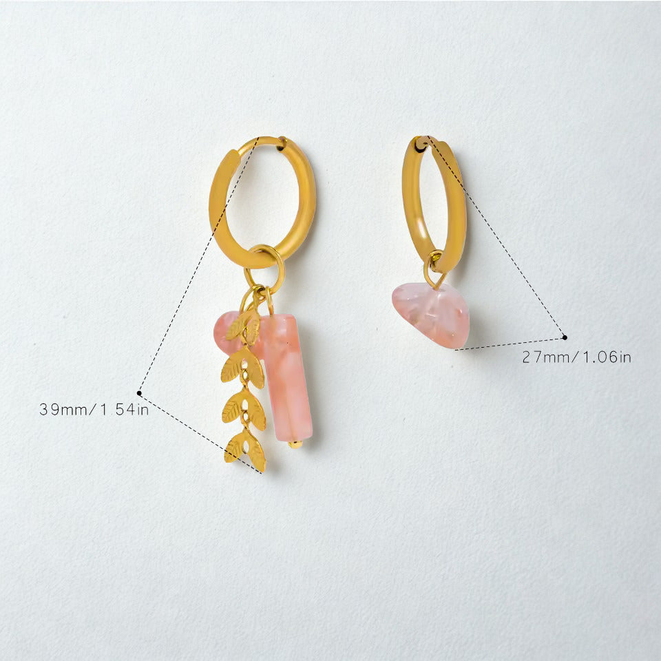 Gold hoop earrings with pink stone and leaf charm on a light gray background