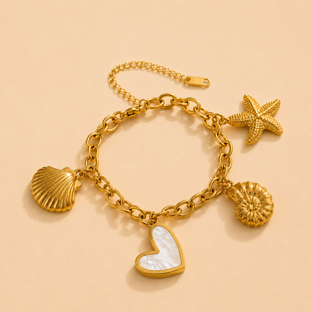 Gold charm bracelet with heart, shell, and starfish charms on a beige background