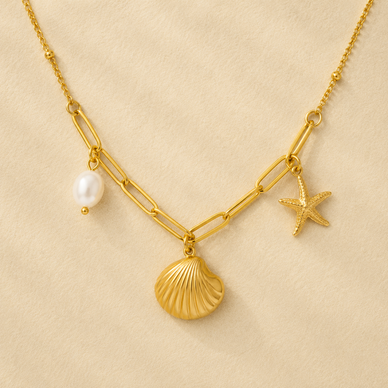 Gold necklace with shell, pearl, and starfish charms on a beige background