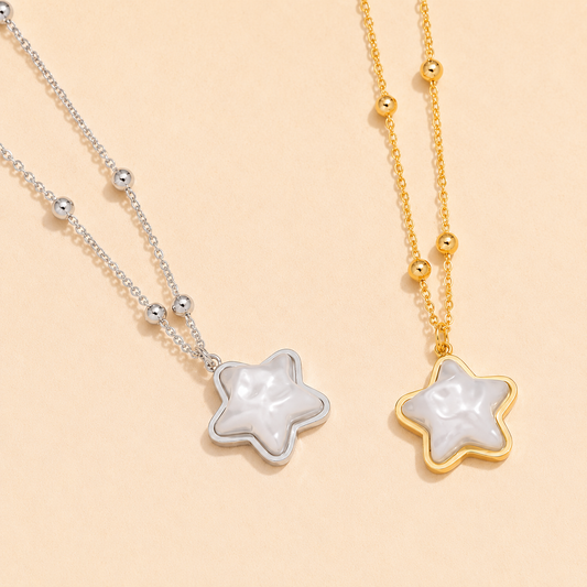 Two star-shaped pendants on gold and silver chains against a beige background