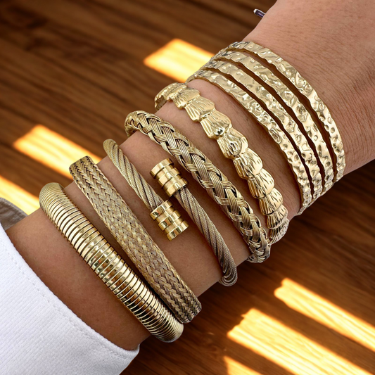 Gold bracelets on a wrist with a wooden background