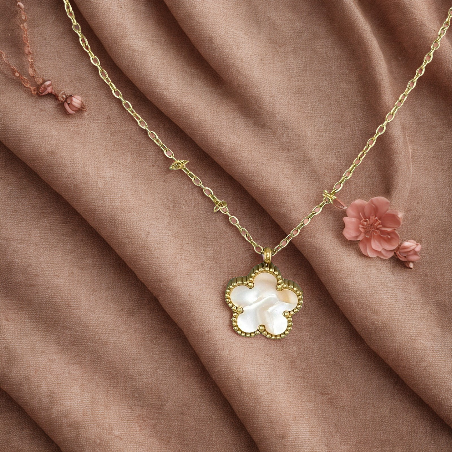 Gold necklace with a floral pendant on a brown fabric background