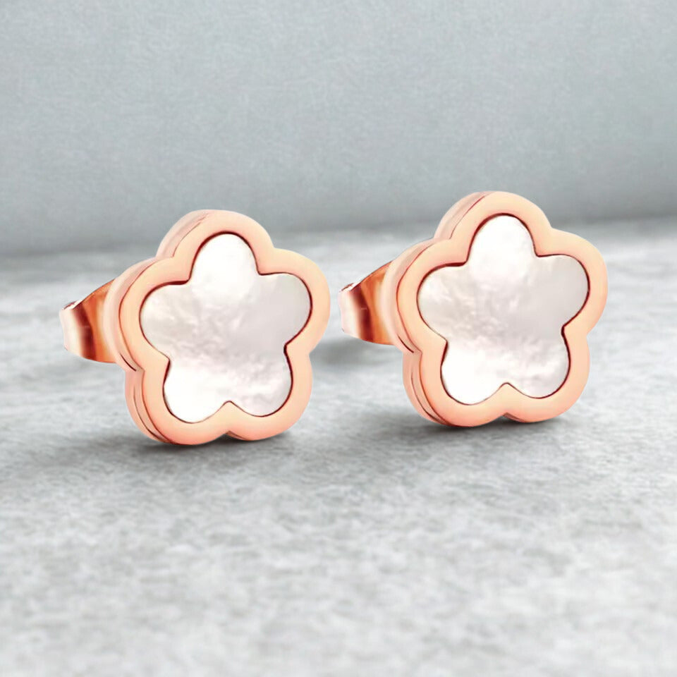Rose gold flower-shaped earrings on a light gray background