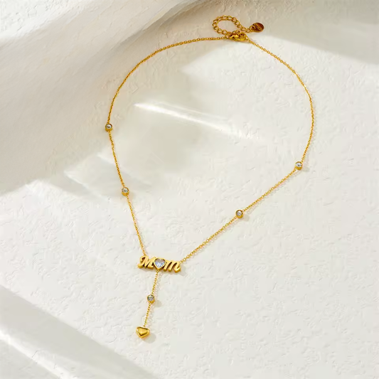 Gold necklace with 'mom' pendant on a white surface