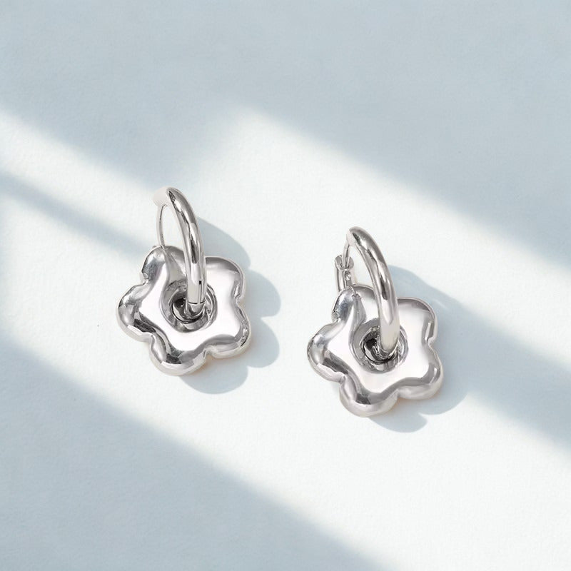 Pair of silver floral earrings on a light gray background