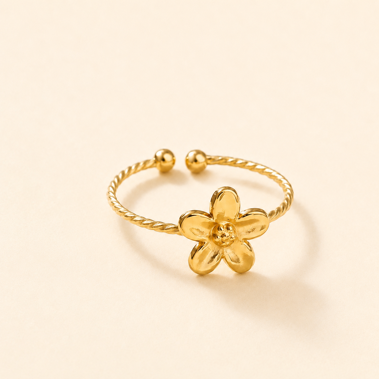 Gold flower-shaped ring on a light beige background