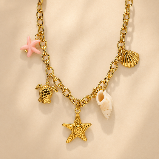 Gold charm necklace featuring a starfish, seashell, conch shell, sea turtle, and pink coastal accent charm.