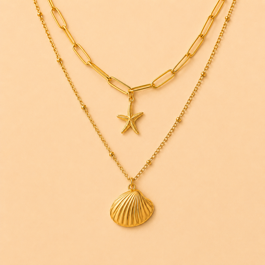 Two gold necklaces with starfish and shell pendants on a peach background