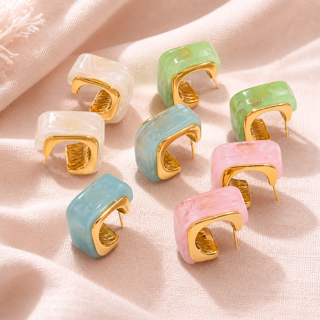 Set of colorful ring holders with gold accents on a soft pink fabric background