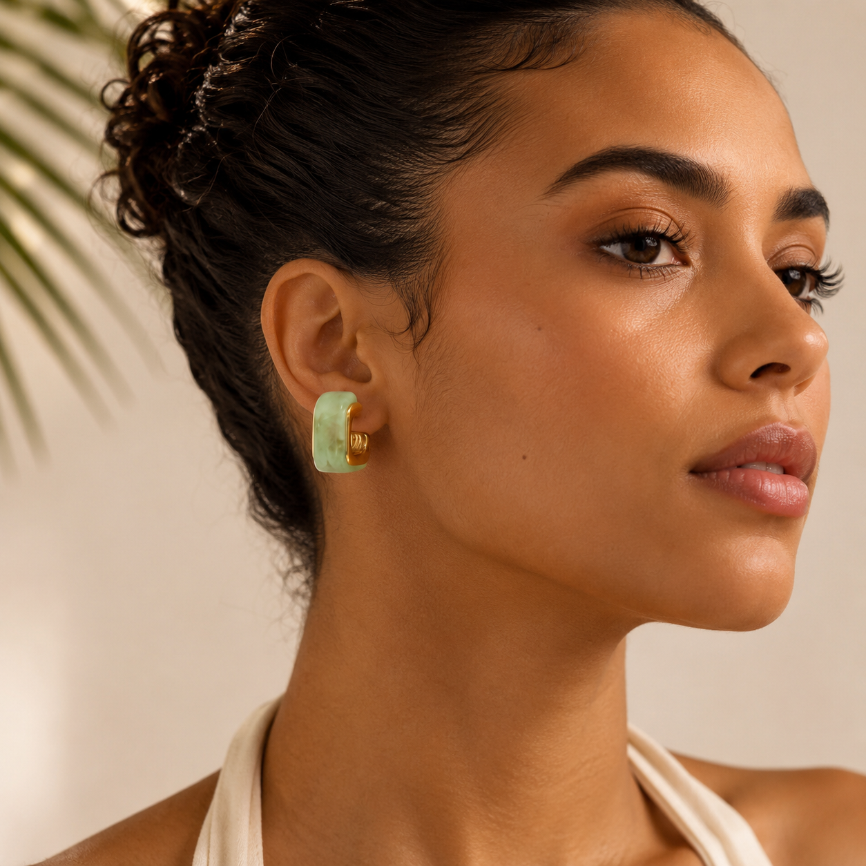 Woman wearing a green earring with a neutral background