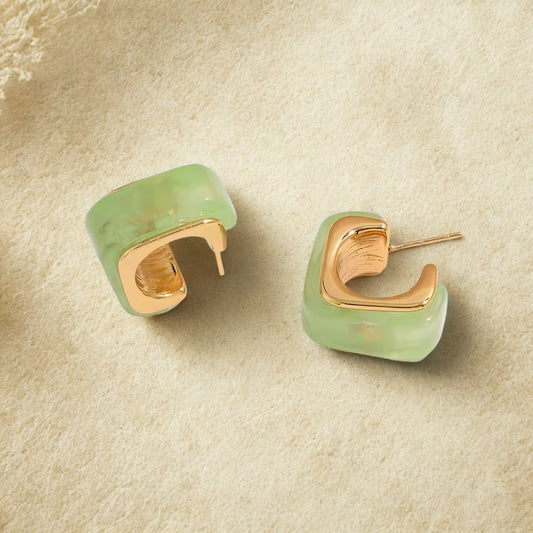 Pair of green hoop earrings with gold accents on a beige surface