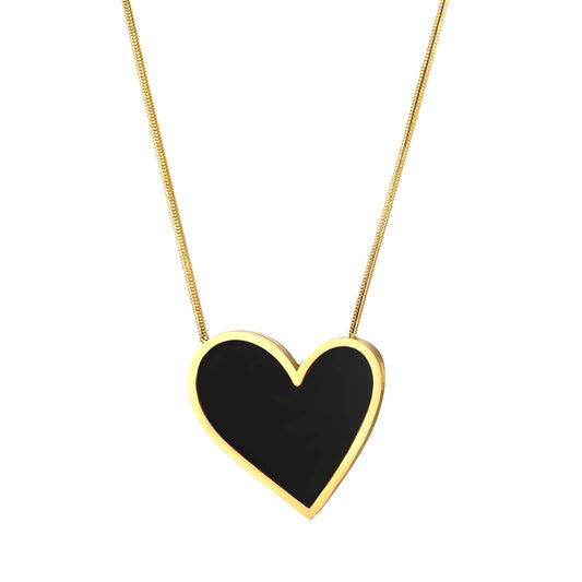 Heart-shaped black pendant on a gold chain against a white background