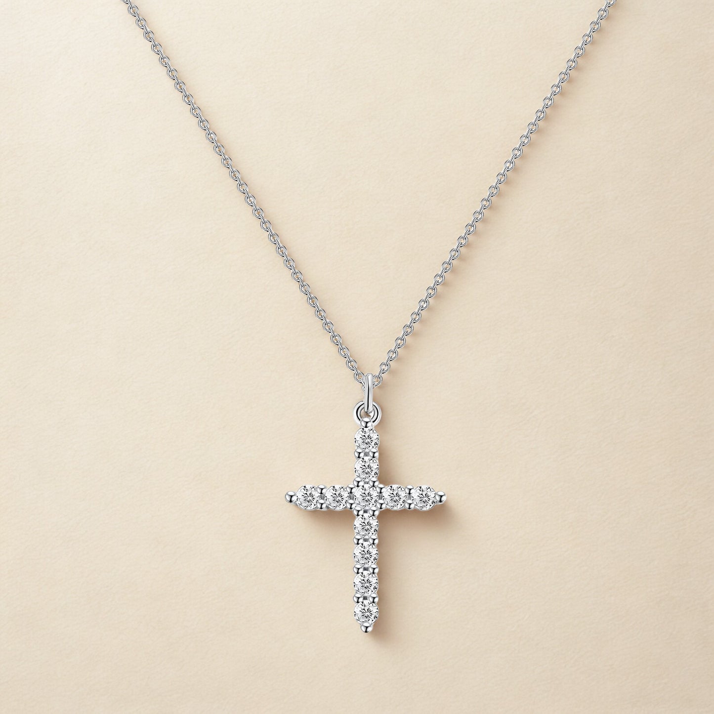 Silver cross pendant necklace on a beige background