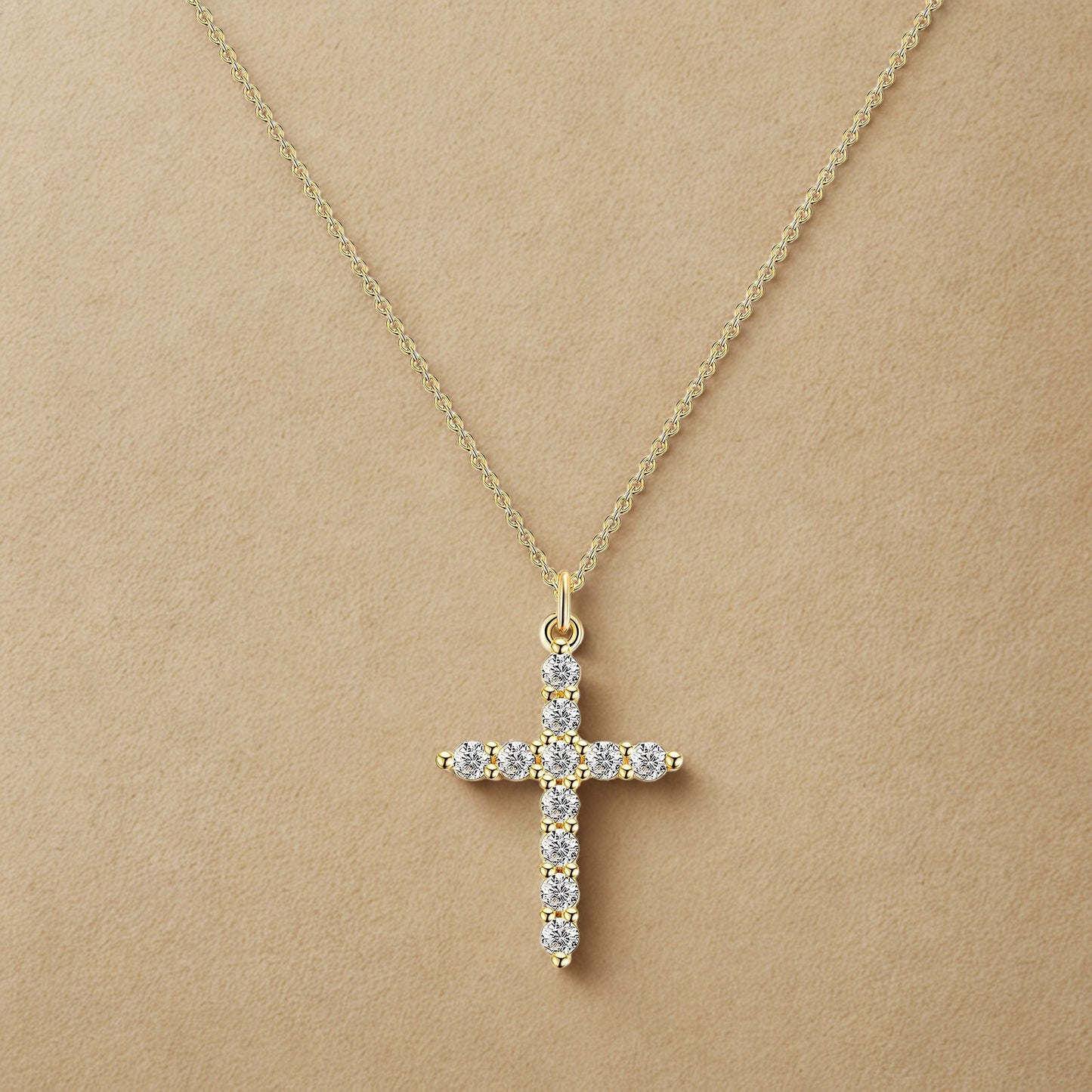 Gold cross necklace with diamonds on a beige background