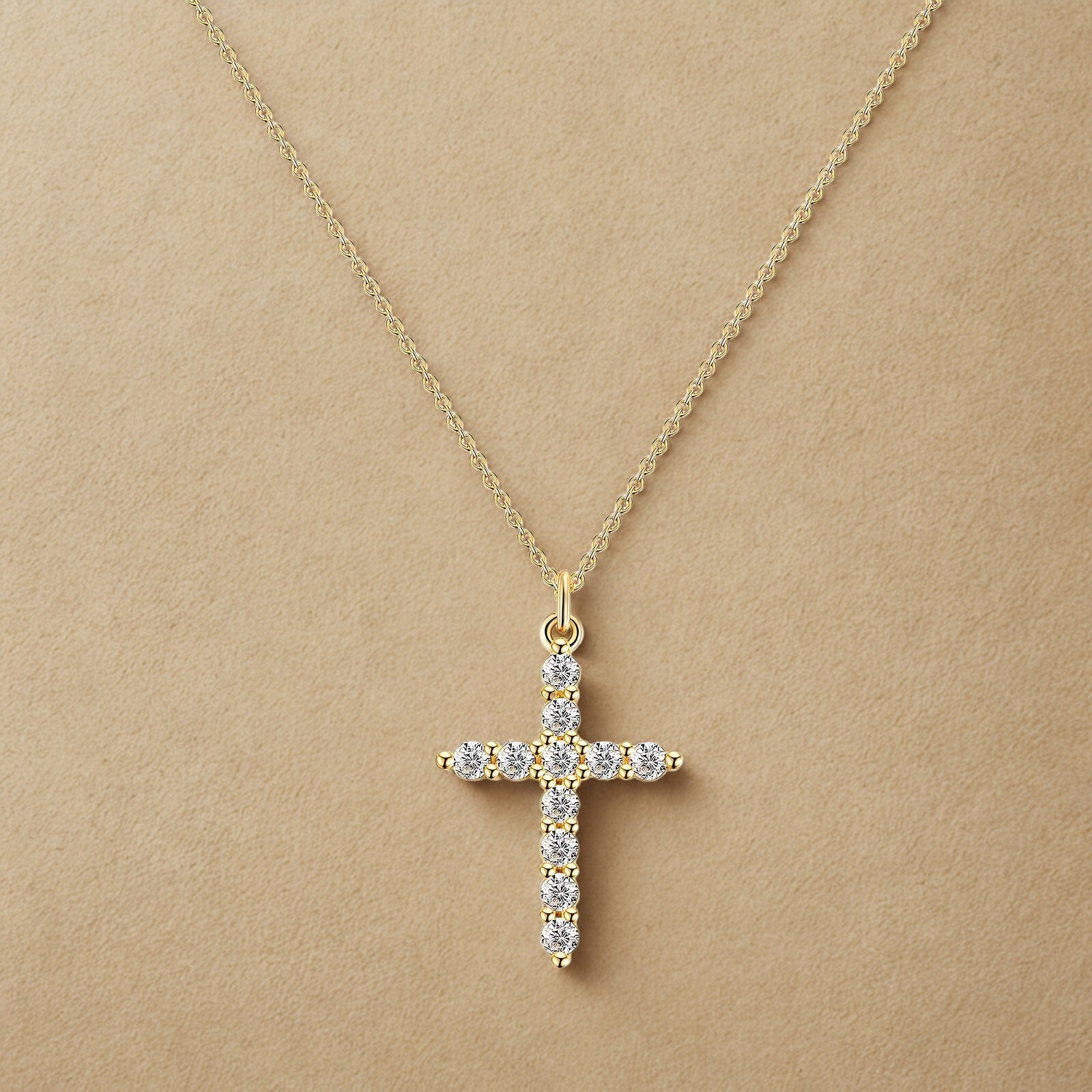 Gold cross necklace with diamonds on a beige background