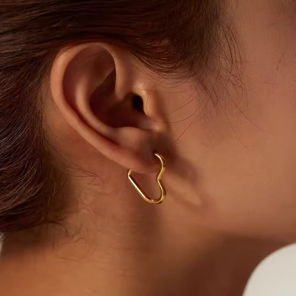 Close-up of an ear wearing a gold hoop earring with a blurred background