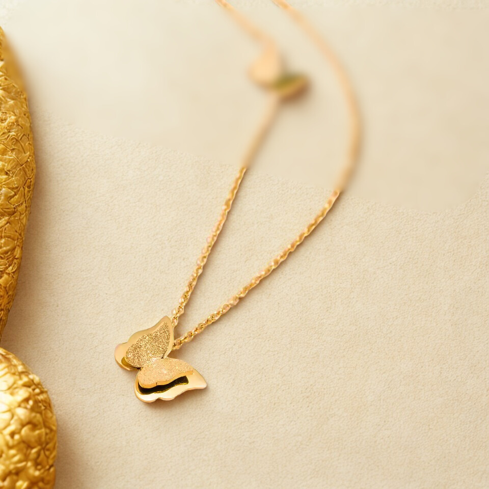 Gold necklace with butterfly-shaped pendant on a beige background