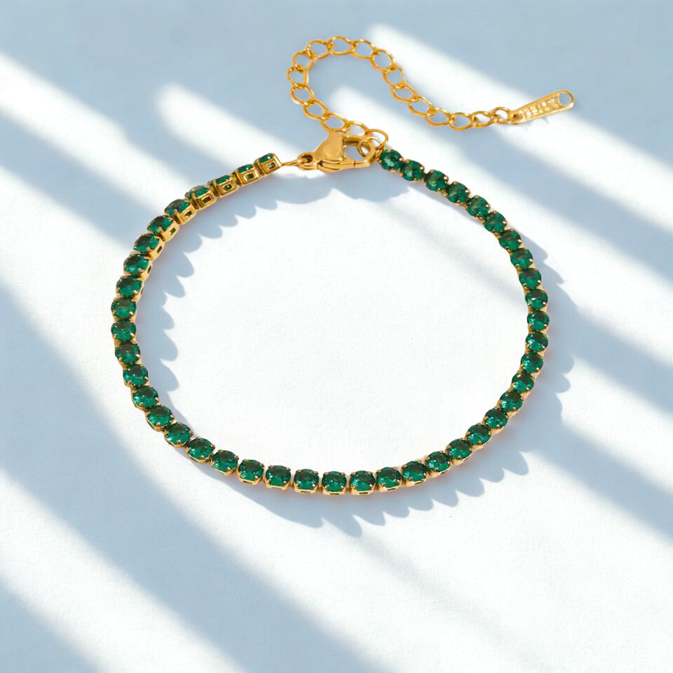 Gold bracelet with green gemstones on a light background