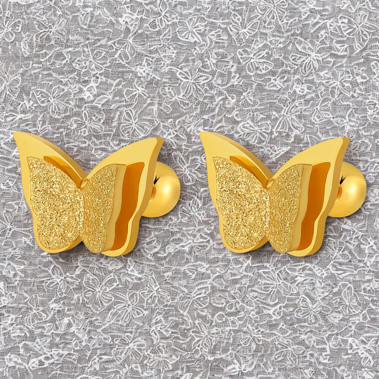 Gold butterfly-shaped earrings on a gray floral patterned background