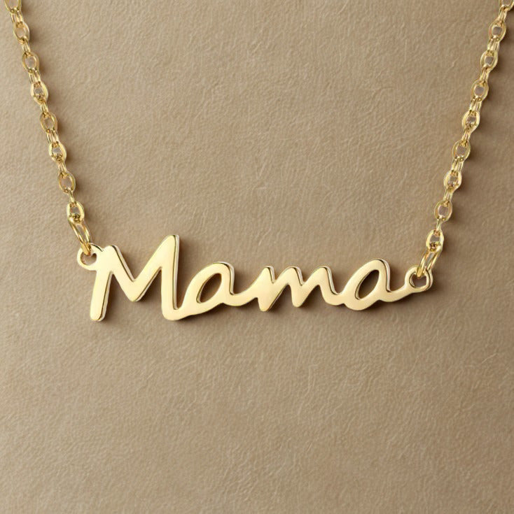 Gold 'Mama' necklace on a beige background. Gold mama script necklace 