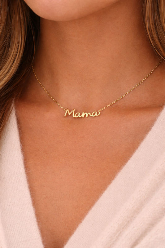 Gold 'Mama' necklace on a person wearing a light pink top.