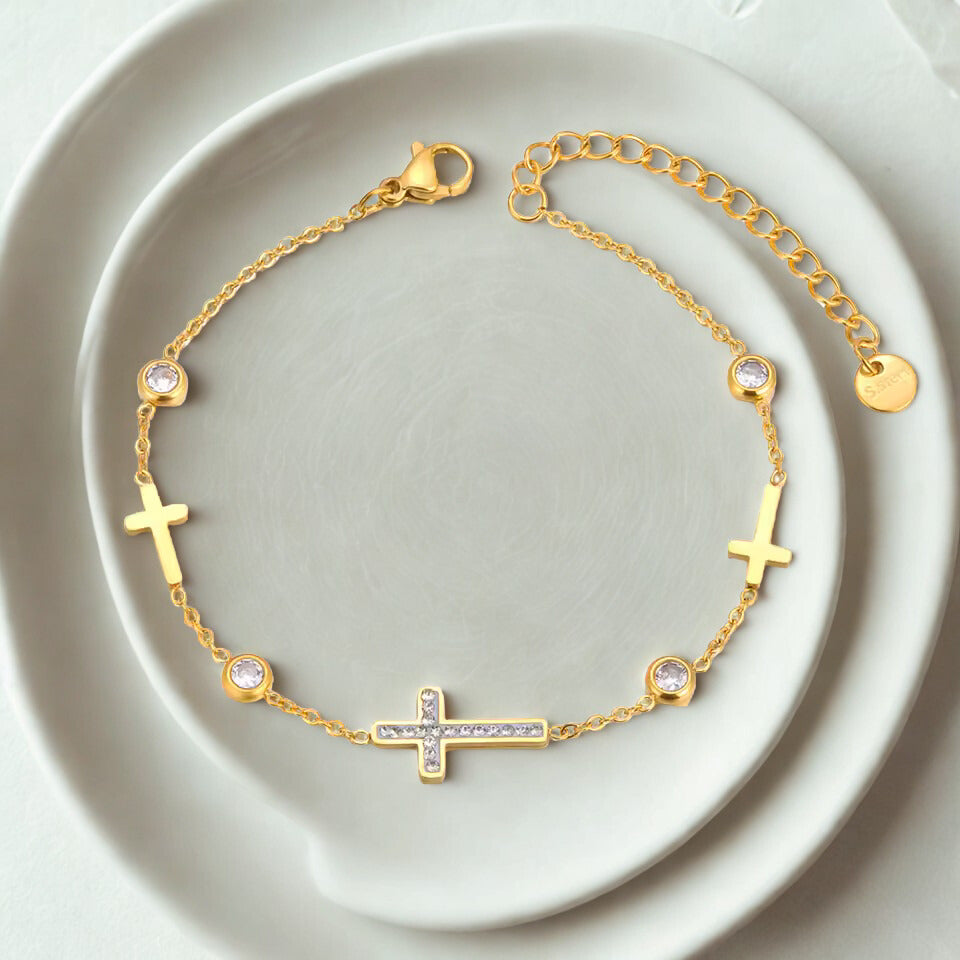 Gold bracelet with cross designs on a white plate