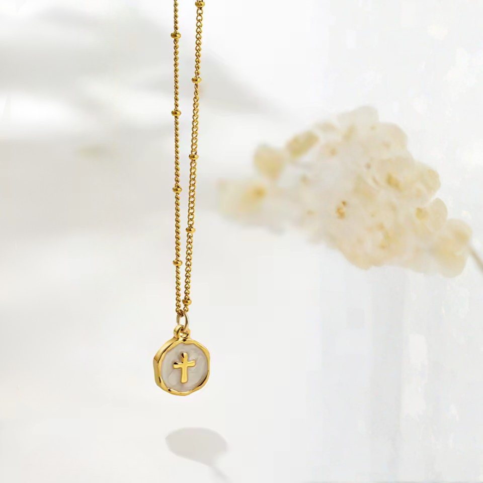 Gold cross on white enamel circle on gold necklace