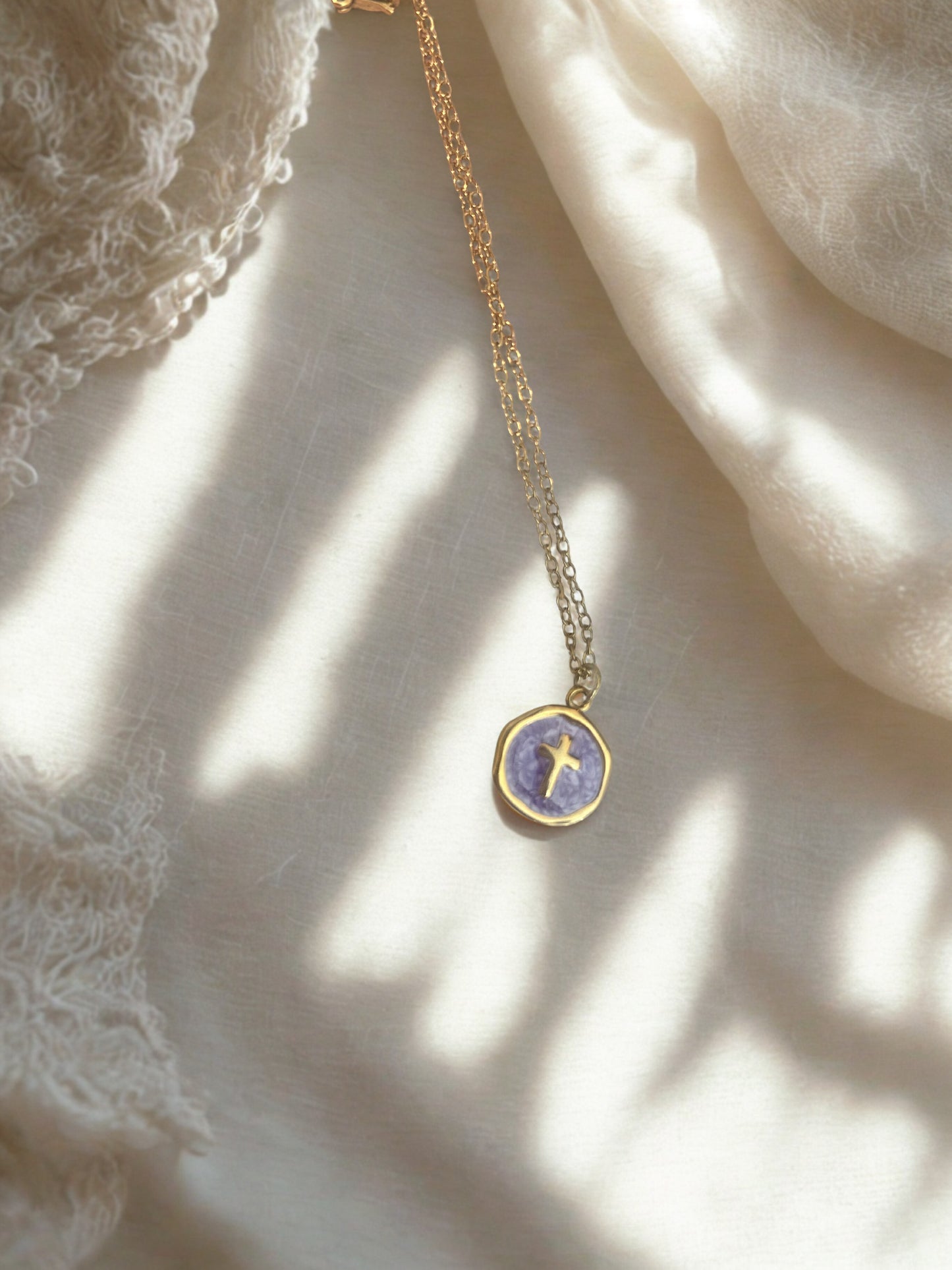Delicate necklace with a purple pendant on a textured fabric background