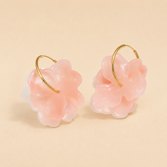Pair of pink floral earrings with gold loops on a beige background