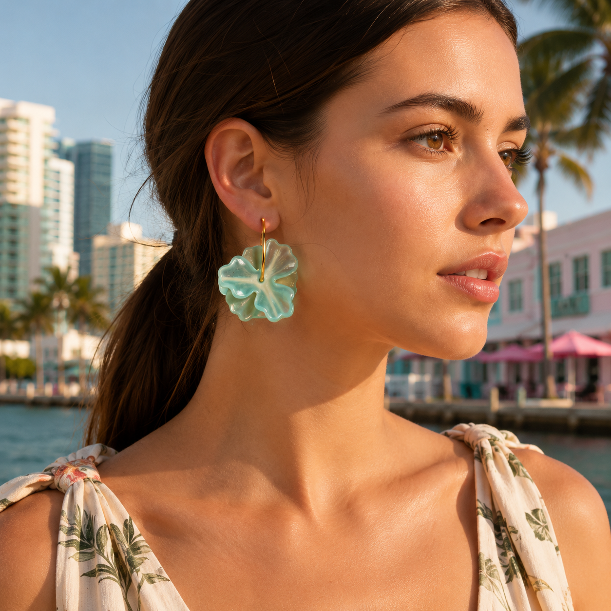 Woman wearing floral earrings with a cityscape and waterfront in the background