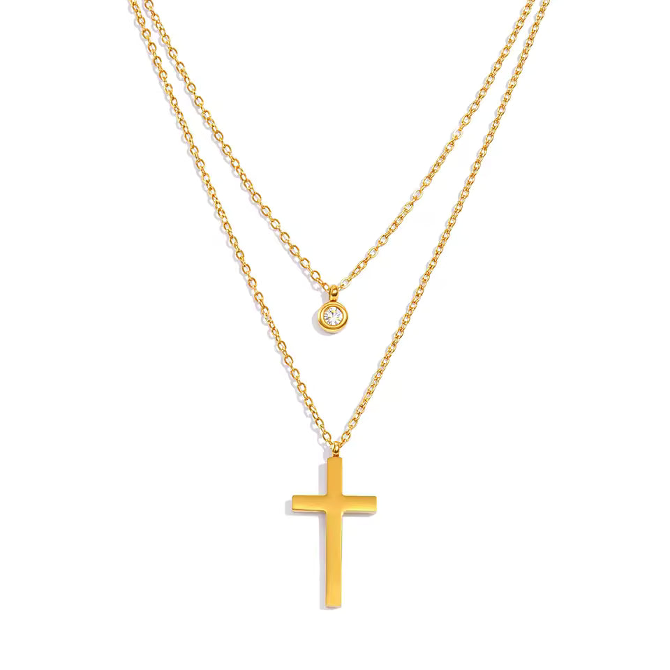 Gold cross necklace with a smaller round pendant on a white background