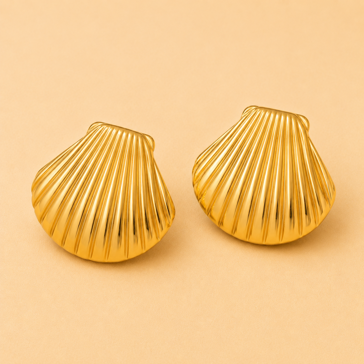 Large gold shell statement earrings with a polished coastal-inspired design.