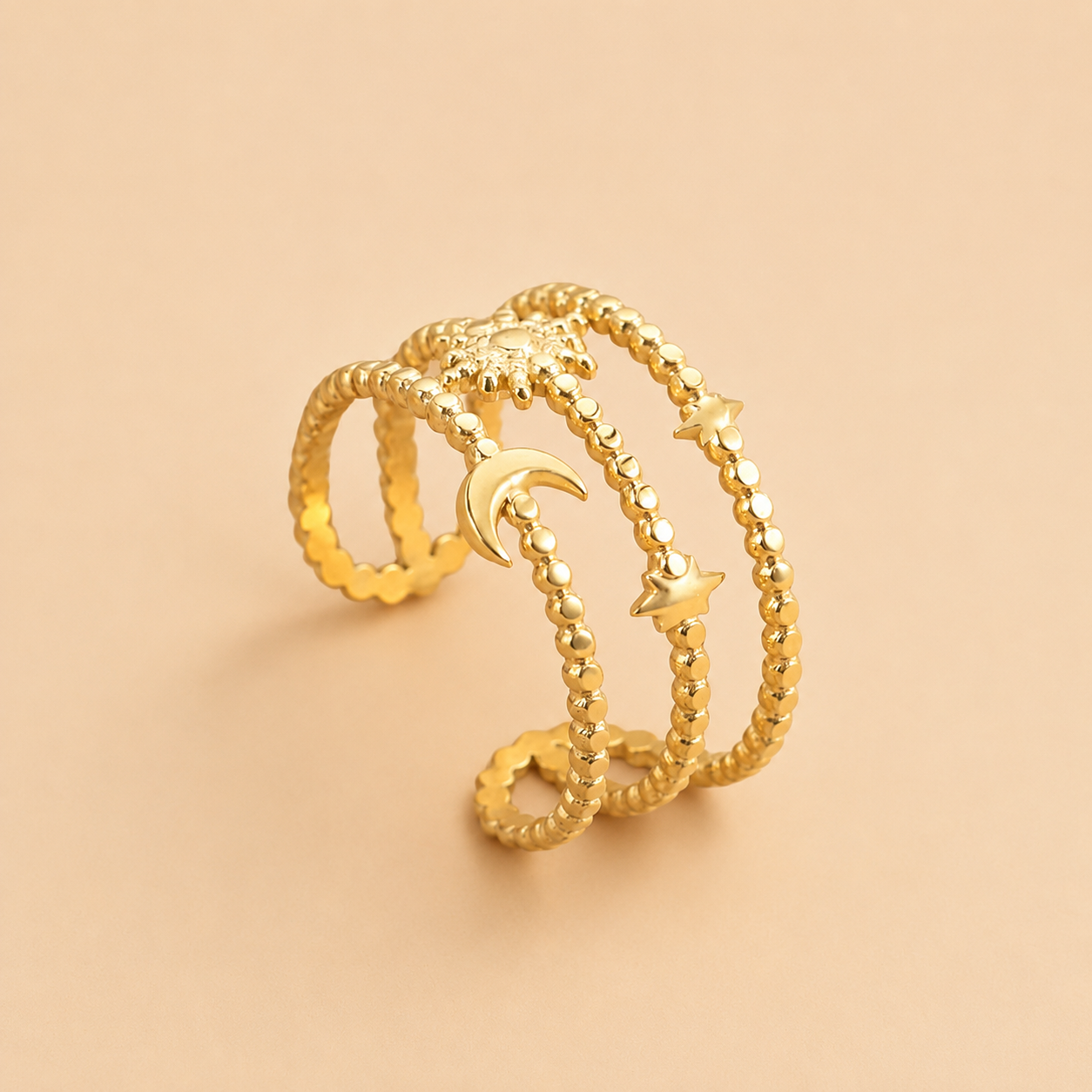 Three gold rings with moon and star designs on a beige background