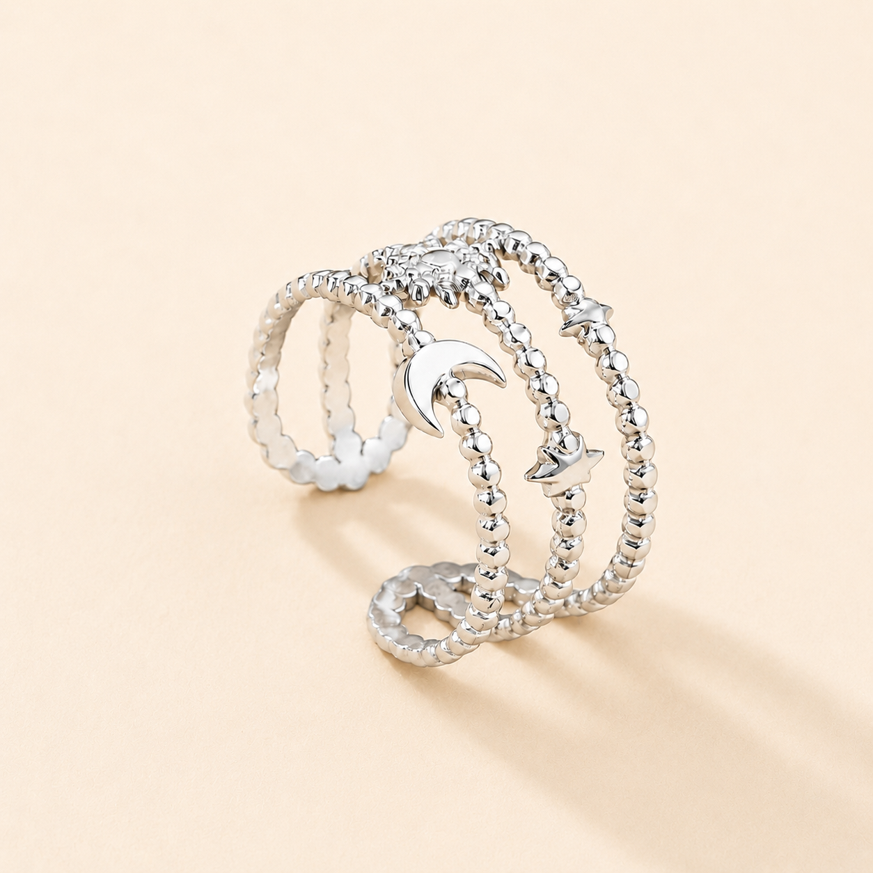 Silver ring with moon and star designs on a beige background