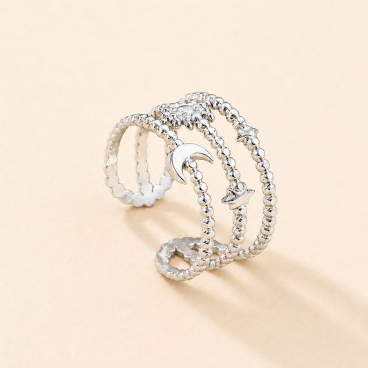 Silver ring with moon and star designs on a beige background